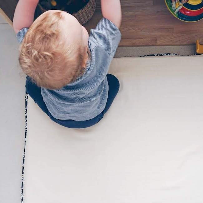 Enfant entre 16 et 24 mois qui attrape un objet dans une étagère Montessori