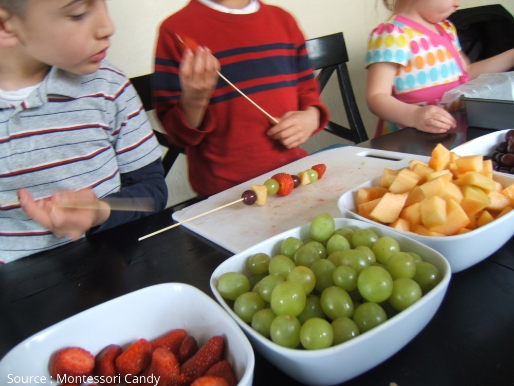 activité Montessori montrant enfants qui préparent de brochettes de fruits