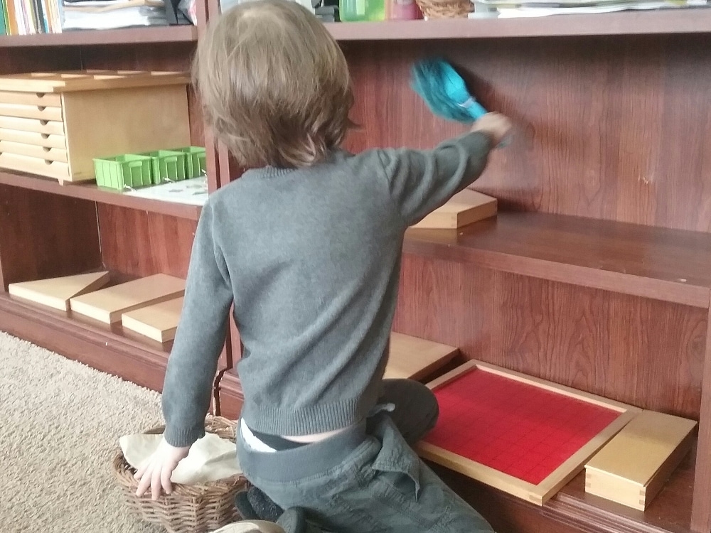 enfant qui dépoussière un meuble Montessori